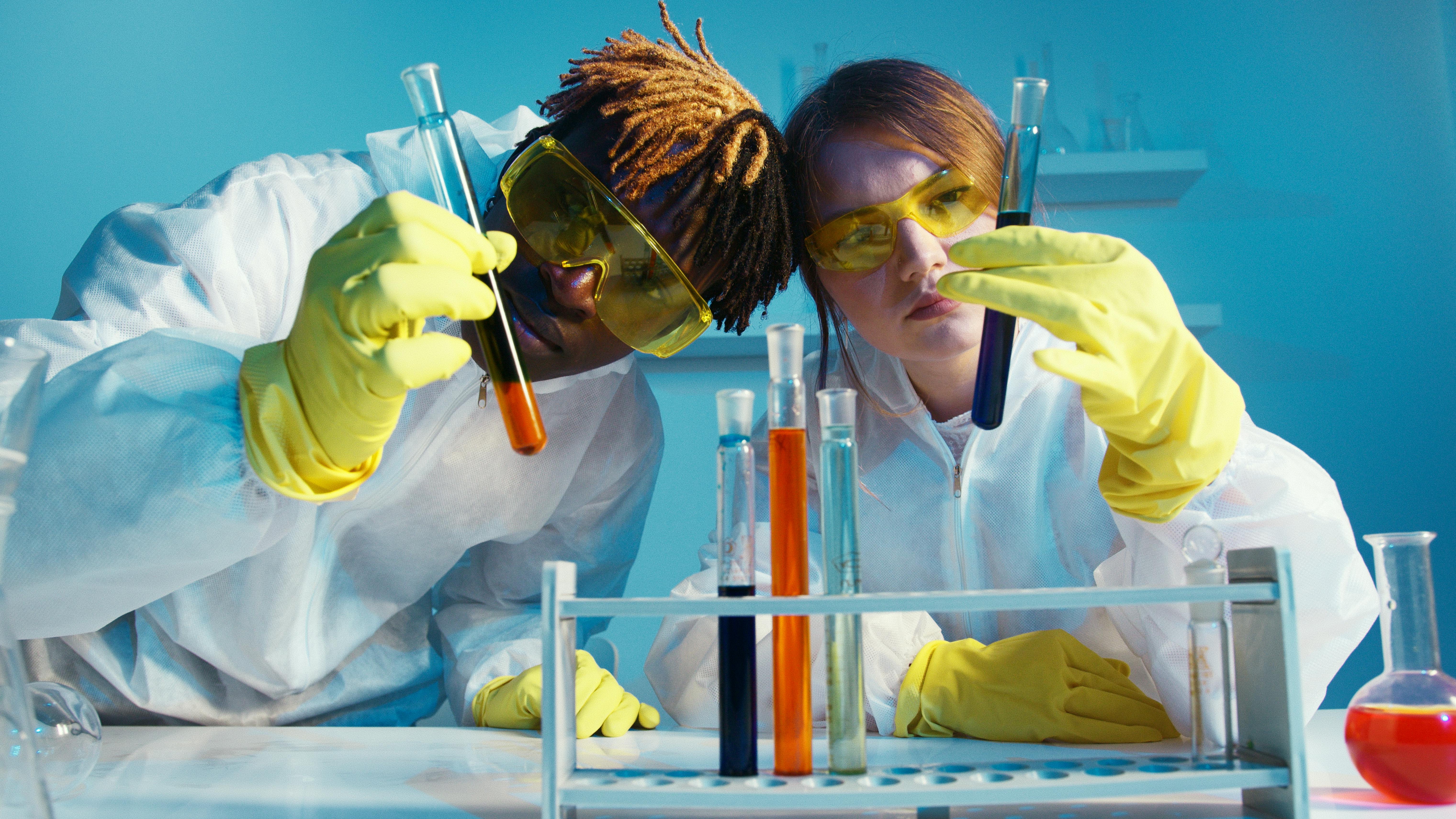 a man and a woman looking at test tubes during a science experiment